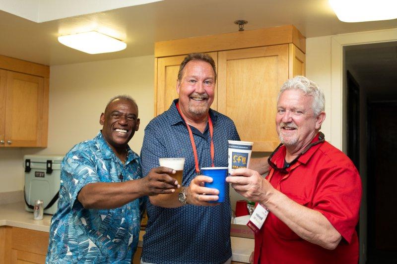 Three alumni cheers their drinks inside a lower townhouse kitchen during Reunion