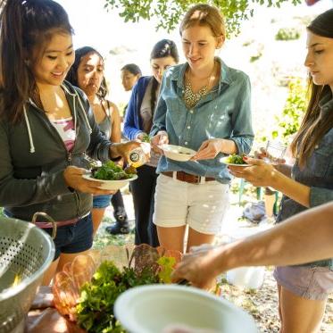 a group of students preparing an outdoor snack/meal from what they harvested in the legacy garden