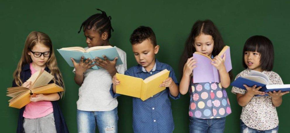Five children standing next to each other, all reading books